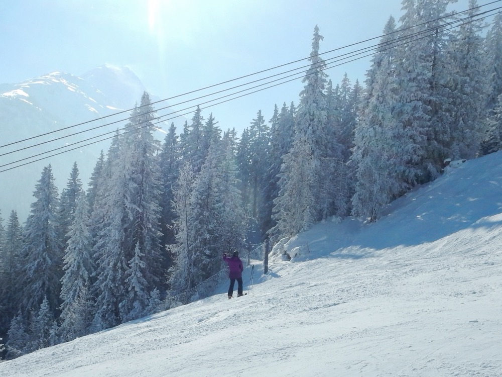 A skier on a piste through snowy forest at St Anton am Arlberg