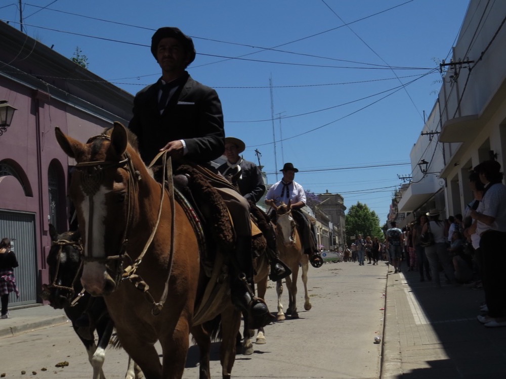 Gauchos on horseback riding down a street in San Antonio de Areco during the Fiesta de la Tradición