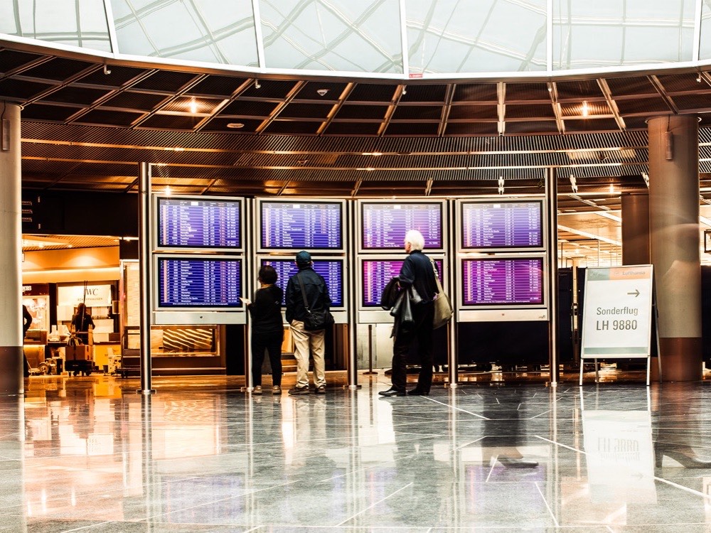 Travellers checking the departure screens in the terminal at Frankfurt Airport