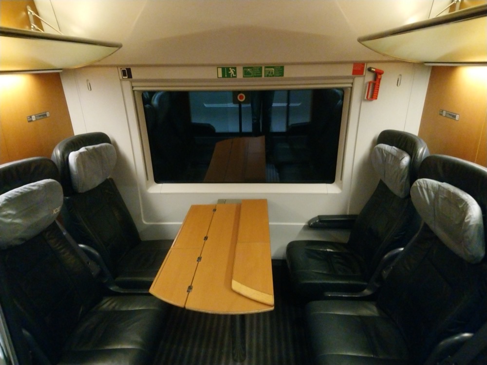 Four leather seats around a table in a first-class compartment of a German ICE train