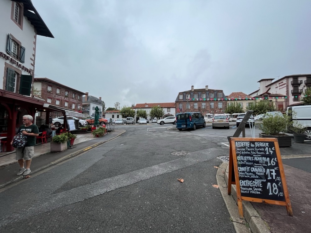 A street in Saint-Jean-Pied-de-Port with café boards and parked cars