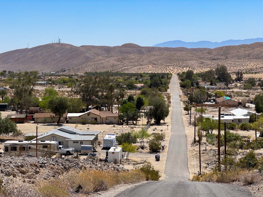 A straight desert road running towards the Indio Hills in California