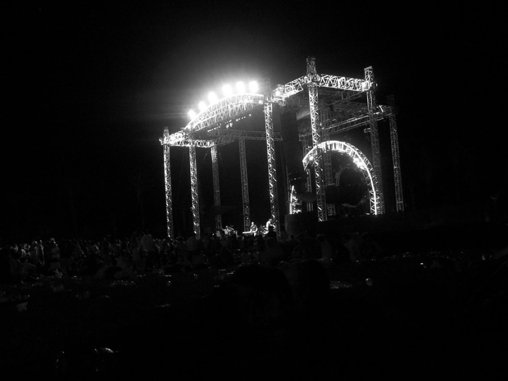 A festival stage lit up at night over a dark crowd at Coachella