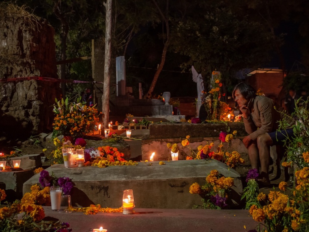 A grave decorated with candles and marigolds at night in the Panteón de Xoxocotlán