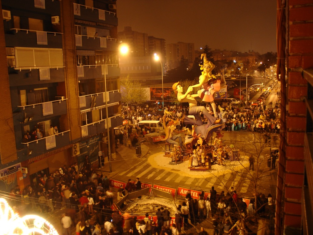 A falla monument lit up at night in a crowded Valencia square