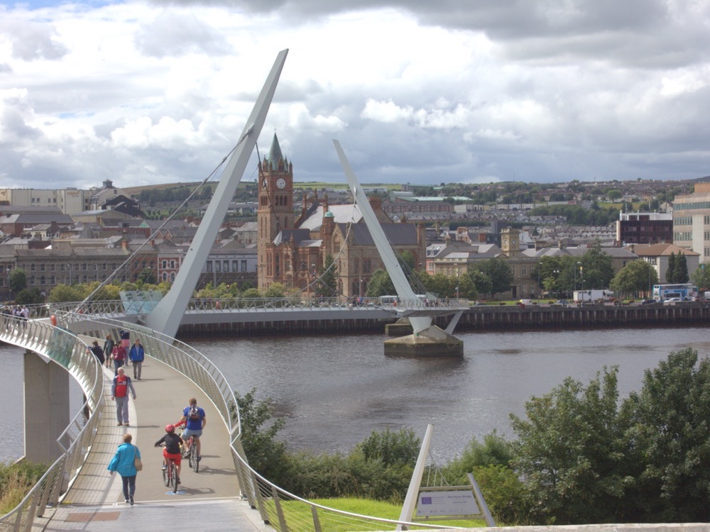 The Guildhall of Derry seen through the white curves of the Peace Bridge over the Foyle