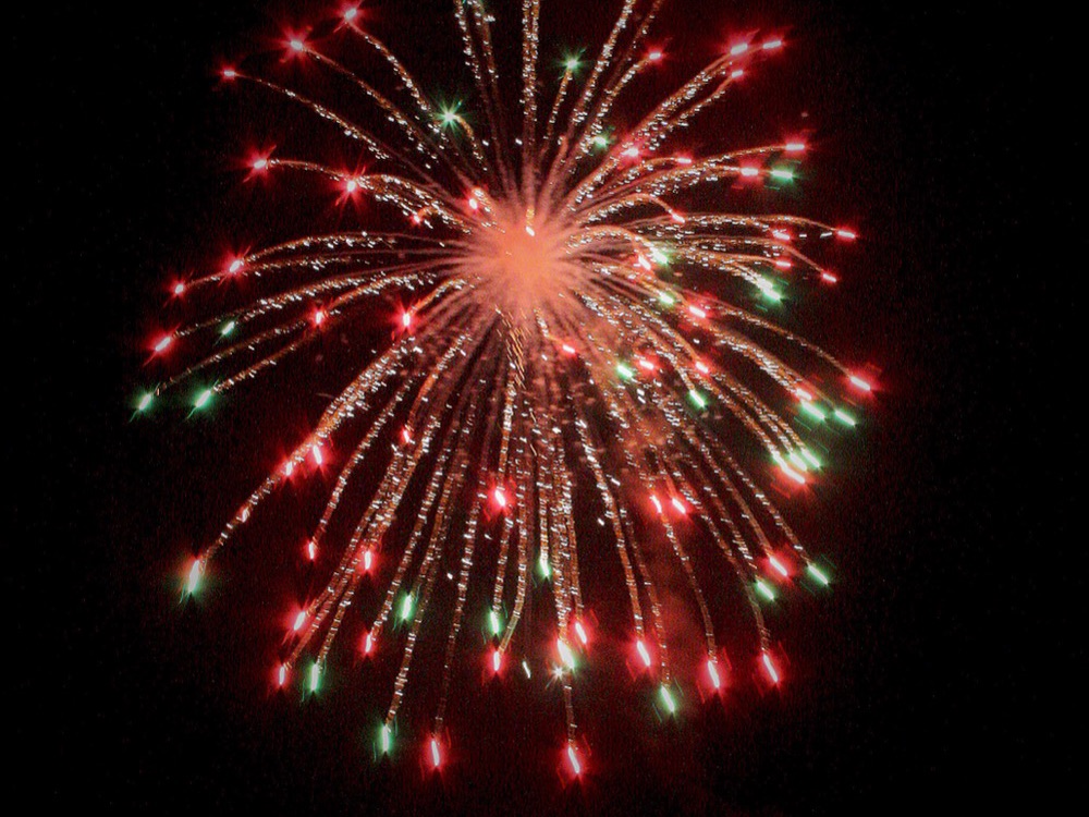 A firework bursting in red and green over Reykjavik at New Year