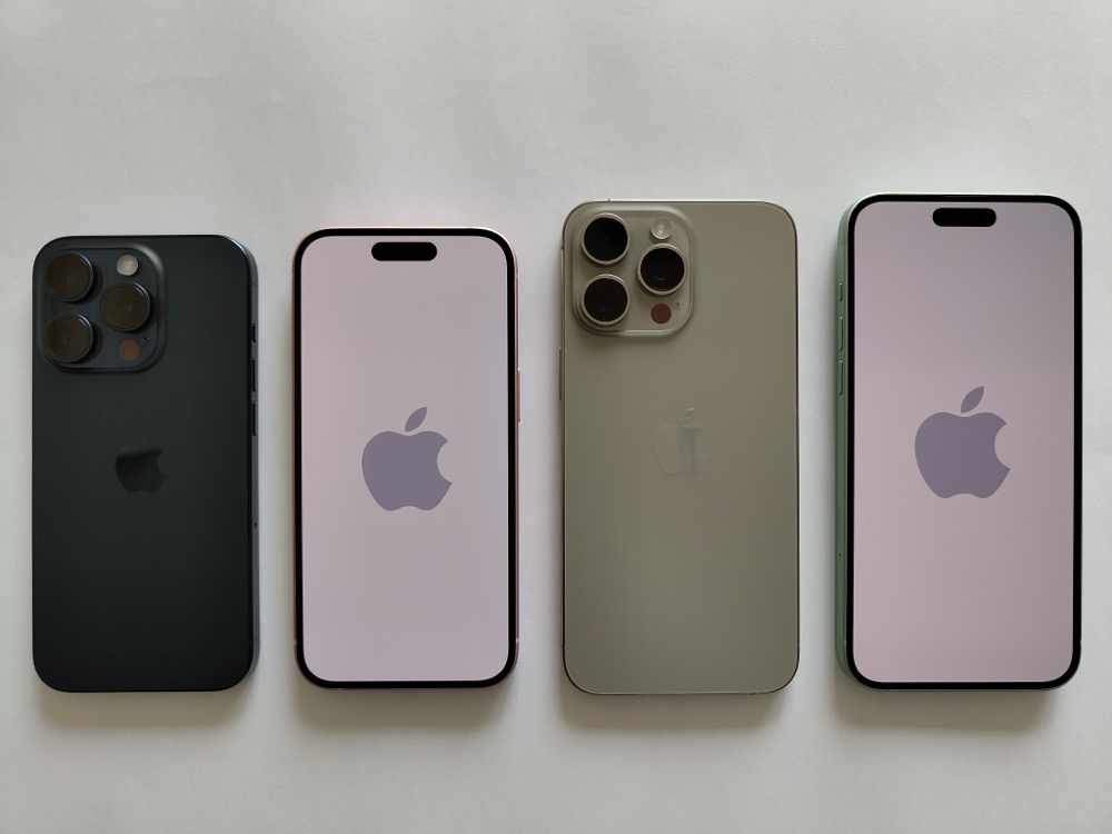 Four iPhone 15 Pro and Pro Max handsets laid on a table