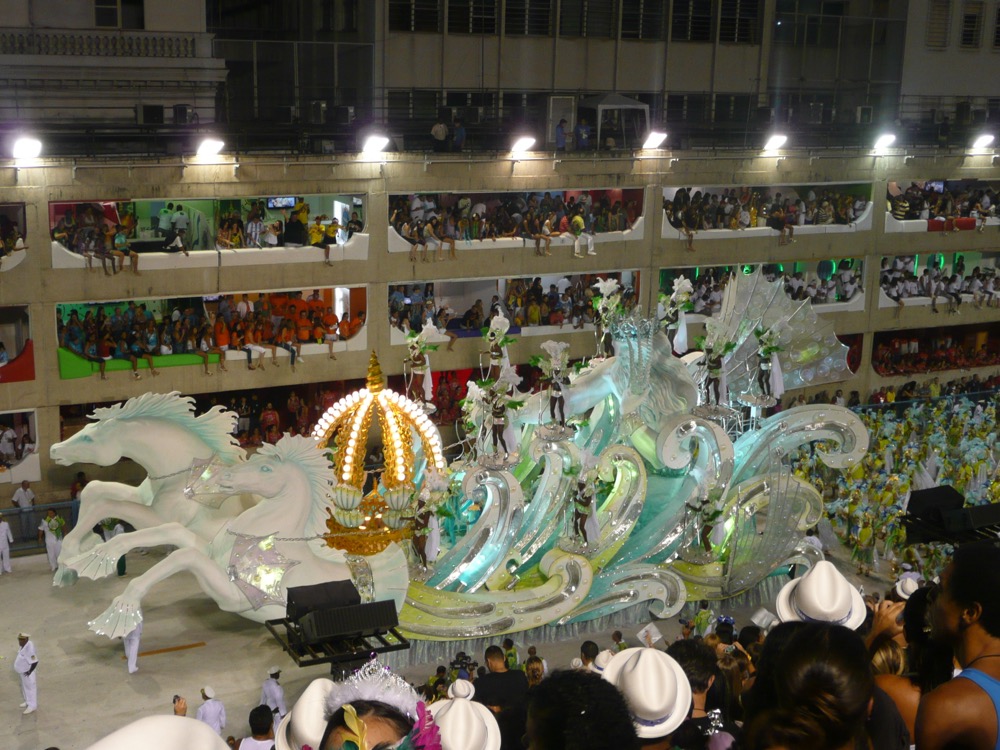 A samba school float passing the packed stands of the Sambódromo at night